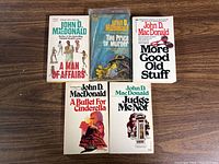 Front view of 5 vintage John D. MacDonald paperback books with their covers displayed.
