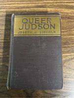 Front cover of 'Queer Judson' showing title, author, and textured brown cover.