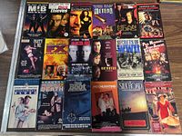 Top view of the 16 VHS movie lot showing cover art of the tapes in two rows. Titles and cover images clearly visible.