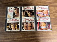 Photo showing all six LaserLight Mozart CDs stacked in two rows on wooden surface.