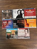 All eight BBC classical music CDs arranged in two rows on wooden surface.