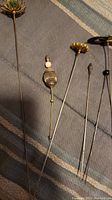Six antique hat pins with varied decorative ends, metal shafts, and pointed tips for securing hats or accessories