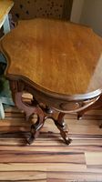 Angle view of scalloped top and carved detail on the table's edge and leg.