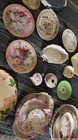Top view of assorted porcelain plates, bowls, small dishes, all with floral decoration and intricate patterns.