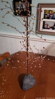 Full view of the tree sculpture showing rock base and numerous wire branches with bead/stone leaves.