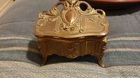 Front view of the Victorian metal jewelry casket showing detailed relief and small legs.