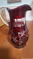 Full view of vintage ruby glass pitcher showing clear glass handle and overall shape.