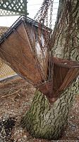 Pair of rusted vintage square tapered metal plant hangers hanging from chains on a tree.
