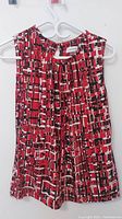 Front view of Calvin Klein sleeveless top showing abstract geometric red, black, and white pattern with keyhole neckline detail.