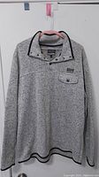 Full view of the grey Free Nature men's sweater with buttoned collar and chest pocket on hanger.