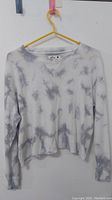 Front view of Hollister long sleeve top with grey and white tie-dye pattern on hanger