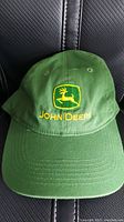 Front view of the green John Deere baseball hat showing the yellow embroidered logo and text.
