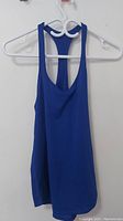 Front view of the blue Lululemon athletic tank top on a hanger against a white wall, showing sleeveless racerback design and scoop neckline.