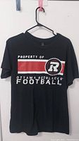 Front view of black Ottawa Red Blacks football T-shirt showing red stripe, logo, and text