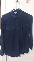 Front view of dark blue long sleeve button-up women's shirt by Calvin Klein, size XS, hanging on a white hanger