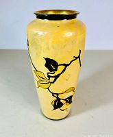 Full front view of vase showing hand painted black and yellow floral branches on cream porcelain with gilded rim.
