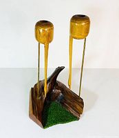 Overall view of the wood carving showing two storks on brass rods mounted on a sculpted wooden base with green patch detail.