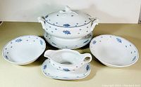 Wide view of the entire set displaying the tureen, two serving bowls and gravy boat with attached underplates.