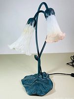 Double lamp standing with both glass shades attached, showing lily pad base and flower petal metal design holding each shade.