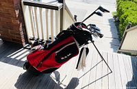 RAM red and black stand golf bag holding full club set on porch