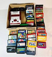 Overview of Nintendo Famicom console and 38 game cartridges arranged around and inside a cardboard box.
