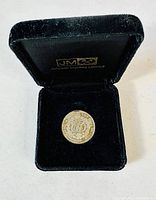 Coin inside original black velvet-lined presentation box from Johnson Matthey Limited, showing coin and box details.