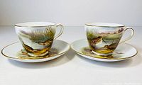 Pair of Spode Woodland series fine bone china tea cups and their matching saucers with detailed bird scenes and gold trim.