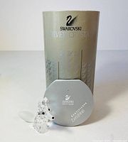 Photo of clear Swarovski fox figurine, certificate booklet, and original silver box with swan logos, all arranged on white surface.