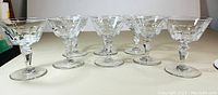 Six vintage Val Saint Lambert signed champagne coupe glasses arranged on a table, showing all glasses in the set.