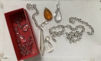 Photo shows a collection of antique chandelier drops including various clear and amber glass teardrops, clear faceted drops, small round glass bead strands, and a long tapered drop, all for restoration or repurposing.