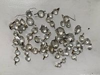 Photo showing a collection of clear glass antique chandelier drops with metal wire hooks, assorted shapes and sizes for restoration or repurposing.