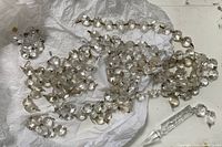 Clear crystal chandelier drops spread on white paper, including round, teardrop, and icicle shaped pieces