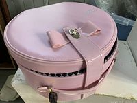 Closed view of the pink round carrying case with bow and clasp closure, displaying overall exterior condition and design.
