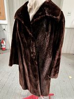 Full view of vintage dark brown beaver fur coat on mannequin in well-lit room with white walls and window, showing lapel collar and classic 1940s style.