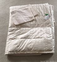 Folded king size quilted duvet with a cream color and subtle stitched pattern.