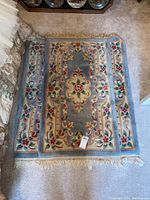Carpet mat showing overall design and fringe edges, soft colors with floral pattern.