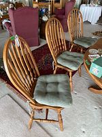 Front view showing four oak chairs with green cushions in a living room setting