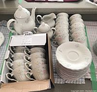 Full set tea pieces including teapot, creamer, sugar bowl, cups in box, and saucers stacked.