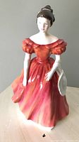 Full front view of the Royal Doulton figurine in a red-orange dress showing facial details and dress.
