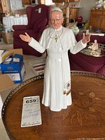 Front view of the Royal Doulton Pope John Paul II figurine with arms open, showing detailed facial features and cross necklace.