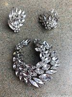 Top view of the Sherman rhinestone brooch and matching clip-on earrings arranged on a surface