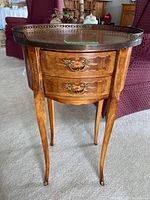 Front view of vintage wooden table with two drawers and metal gallery edge on top.
