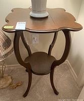 Vintage oak side table shown from a side view with visible curved legs and circular lower shelf. Top surface partially showing separation at the seams.
