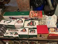 Multiple boxed Department 56 Village Accessories and North Pole Series items, Holiday Time gingerbread bridge, street lamps and snow packs arranged on a table