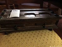 Exterior view of the vintage wooden jewelry box with dark finish and metal latches, closed.