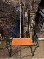 Green metal garden bench with orange padded seat, aerator tool, curtain rods and pot rack arranged behind bench, blue tarp in packaging to the left