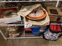 Spode Christmas Tree Christmas cheese set plate and knife in original box on a metal shelf along with Halloween bowl and dog bed cover below