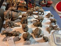 Twenty resin elephant figurines arranged on a table, each with a faux stone nameplate