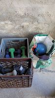 Wide view of three containers holding assorted exercise weights and medicine balls in various colors.