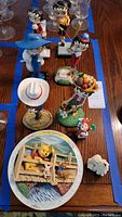 Overhead photo showing multiple Betty Boop figurines, Winnie the Pooh collector plate, and small decorative ornaments arranged on a table.